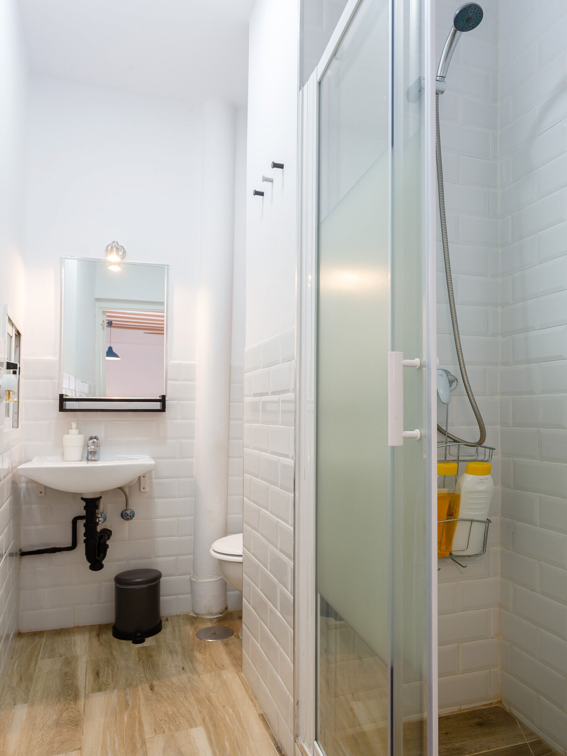 A modern bathroom with a glass shower enclosure, a white sink with a mirror above it, and a toilet.
