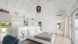 A modern bedroom with a large bed, a desk, and a view of the outdoors. - SUNSET VILLA ANGEL **** (saint barthelemy)