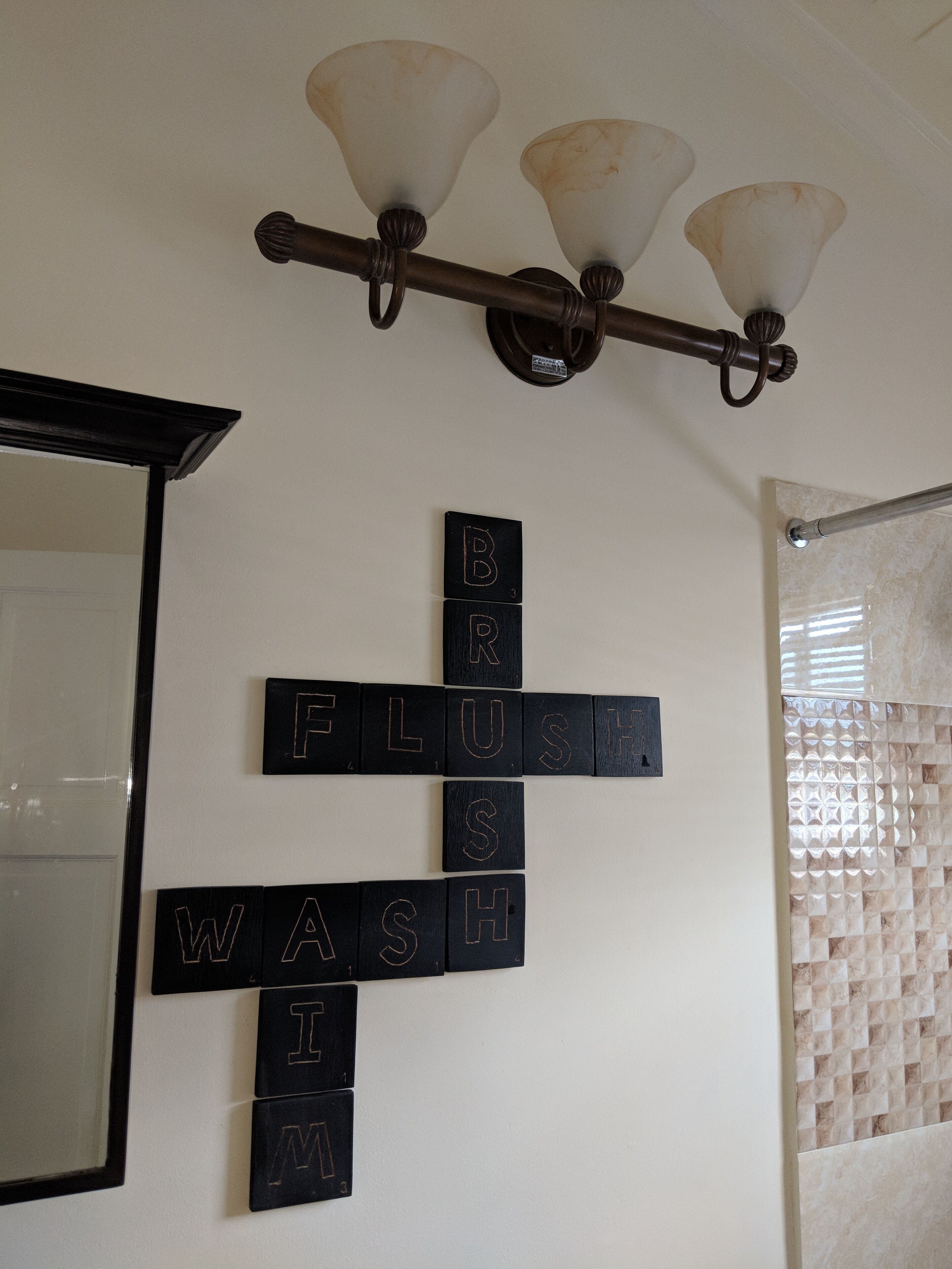 Een badkamer met een wandlamp en een letterspelletje.
