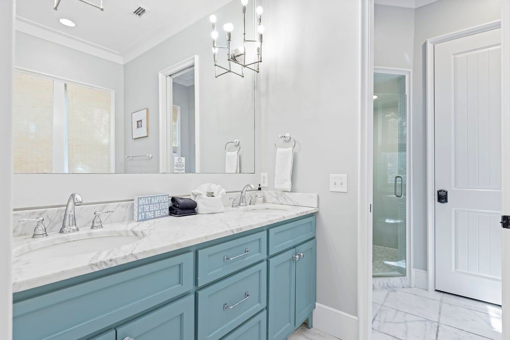 A bathroom with a large mirror, two sinks, and a shower area.