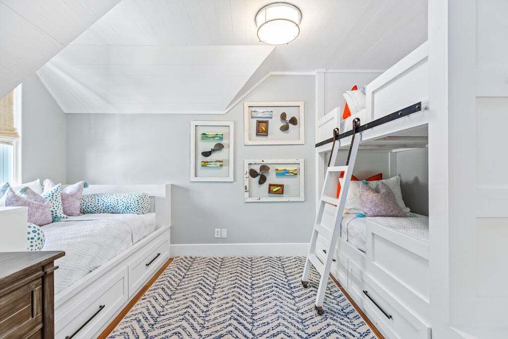 Une chambre avec deux lits superposés, une échelle, un tapis à motifs et des œuvres d’art mural.