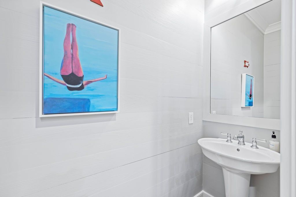 A bathroom with a large framed artwork of a diver, a white sink, and a mirror above it.