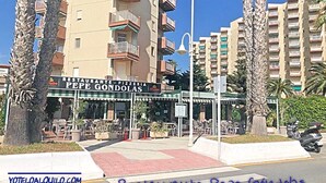 Um restaurante chamado Restaurante Pepe Gondolas com mesas ao ar livre, rodeado por edifícios altos e palmeiras.
