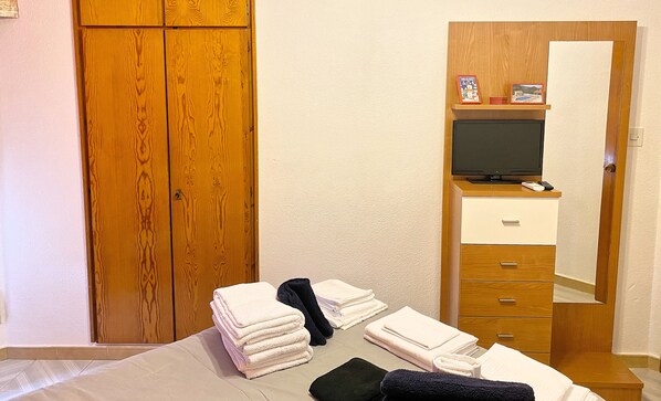 Una habitación de hotel con una cama, un armario de madera, un televisor y un espejo.