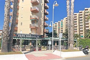 A restaurant named Restaurante Pepe Gondolas with outdoor seating, surrounded by tall buildings and palm trees.