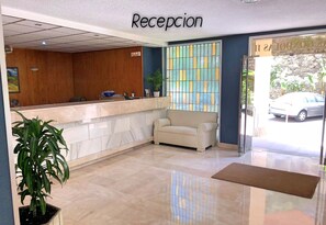 A reception area with a reception desk, a sofa, and a potted plant.