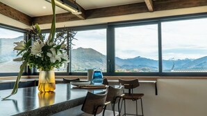 Une cuisine moderne dotée d’un grand îlot central, de tabourets de bar et offrant une vue sur les montagnes grâce à de larges fenêtres.