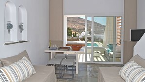 En rummelig suite med balkon, spiseplads og udsigt til pool og bjerge.