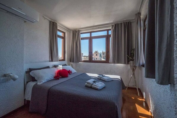 A hotel room with a bed, a window, and a plant.