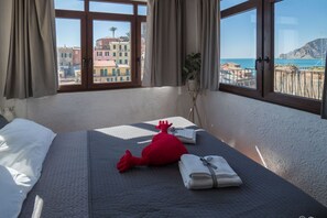 Una habitación de hotel con una cama, un peluche rojo y una toalla doblada con cuidado.