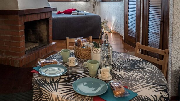 Ein gemütliches Zimmer mit Kamin aus Ziegelsteinen, einem runden Tisch gedeckt mit Tellern, Tassen und einer Snackauswahl.