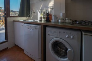 Une cuisine compacte équipée d’un lave-linge, d’un lave-vaisselle et d’une cuisinière à gaz.