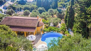 Eine Villa mit Swimmingpool, umgeben von Bäumen und mit Blick auf ein Gewässer.