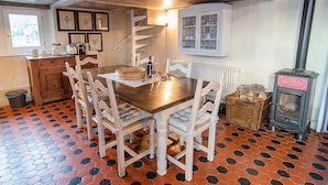 A dining area with a wooden table and chairs, a radiator, a stove, and a window with a view.