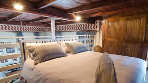 A bed with a white frame and a beige bedspread, a wooden wardrobe, and a chevron-patterned wall.