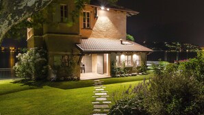 A two-story house with a tiled roof, a stone facade, and a well-maintained lawn.