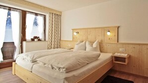 Una cama doble con cabecera de madera, una mesita de noche y una pequeña repisa.