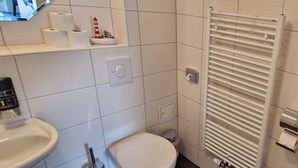 A bathroom with a toilet, sink, and a white radiator. - Double room 1 - Ankes Pension - Object 28383 (Rostock)