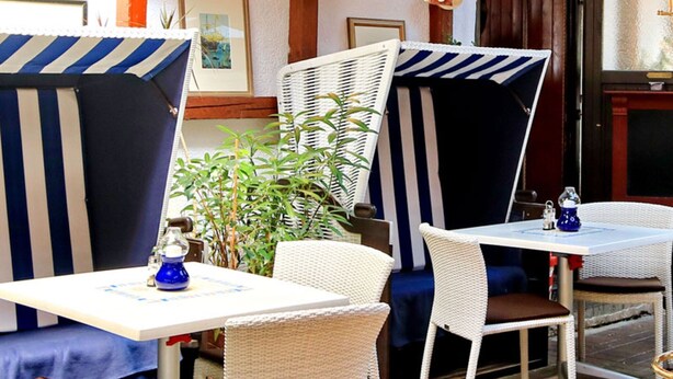 An outdoor seating area with striped awnings, wicker furniture, and a hot air balloon decoration. - Double room 1 - Ankes Pension - Object 28383 (Rostock)