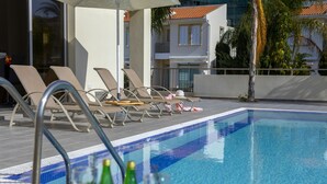 Una piscina con sillas de descanso y una mesa con botellas.