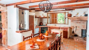 A rustic kitchen with wooden beams, a hanging light fixture, and a tiled floor. - CAN CORRÓ - Villa with private pool in Alcudia. Free WiFi (Alcúdia)