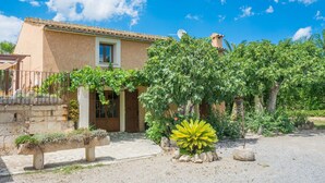 A house with a tiled roof, a front door, and a small window. There is a garden with a bench and a large plant. - CAN CORRÓ - Villa with private pool in Alcudia. Free WiFi (Alcúdia)