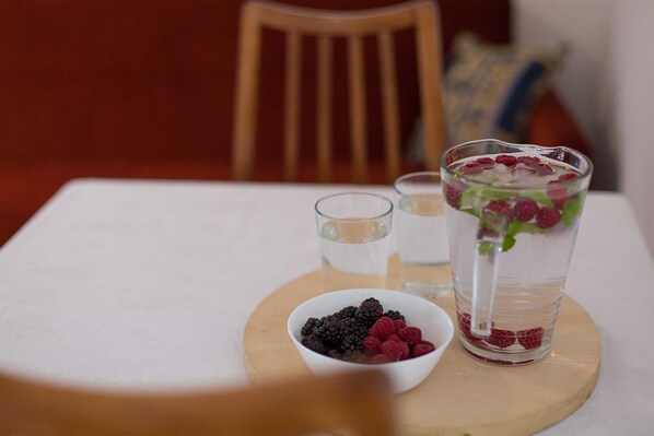 Ett bord med ett glas vatten, en skål med bär och en kanna med is och bär.