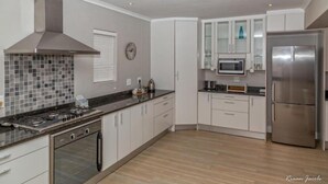 A modern kitchen with white cabinets, a stainless steel range, a microwave, and a refrigerator.