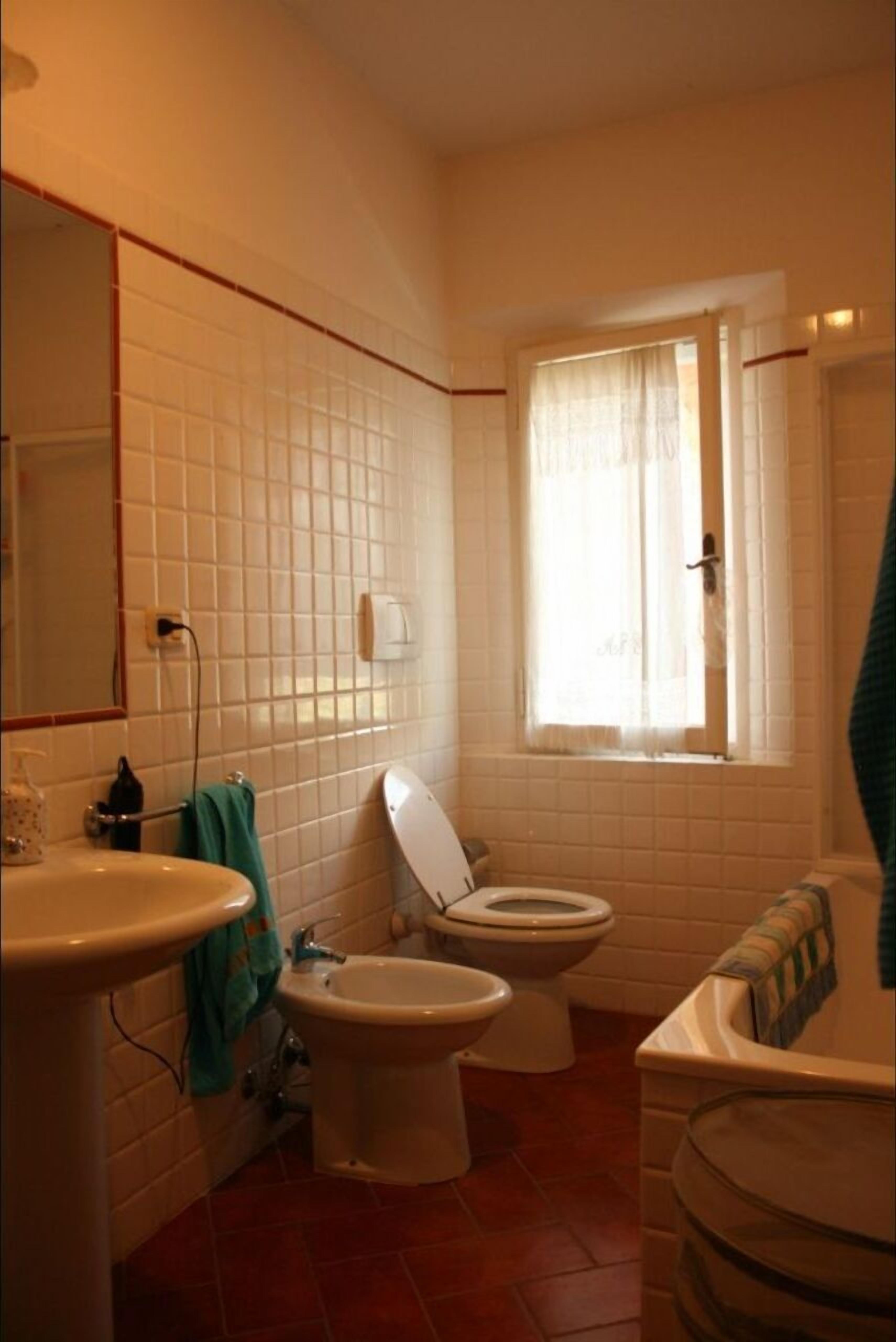 A bathroom with a sink, two toilets, a bidet, and a bathtub.