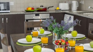 A breakfast setting with plates, glasses of orange juice, and fresh fruits. - Protaras Palm Suite 207 (Protaras)