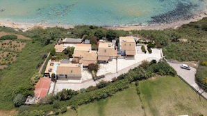 Vista aérea de una propiedad costera con varias construcciones, una piscina y una playa.