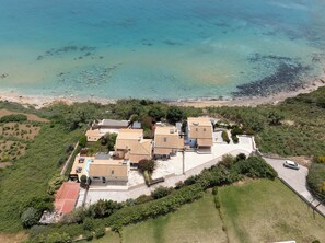 An aerial view of a coastal property with multiple buildings, a swimming pool, and a beach. -  Sea Front Villa Private Pool, Wonderful Views of Avithos Beach. Airport 10 mins (Svoronata, Kefalonia)
