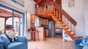 Amplia sala de estar con escalera de madera, cocina equipada con electrodomésticos modernos y comedor con mesa y sillas.