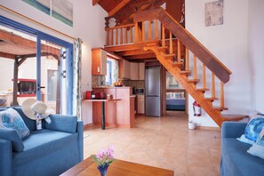 A spacious living area with a wooden staircase, a kitchen with modern appliances, and a dining area with a table and chairs. -  Sea Front Villa Private Pool, Wonderful Views of Avithos Beach. Airport 10 mins (Svoronata, Kefalonia)