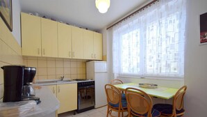 Una cocina compacta con armarios amarillos, una estufa y una mesa de comedor con cuatro sillas.