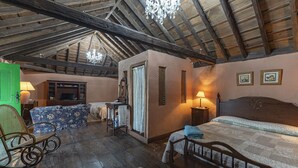 Un dormitorio rústico con techo de madera, una cama, una silla, una mesa y una puerta verde.