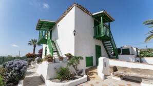 Un edificio blanco con balcones verdes y un patio con tejas.