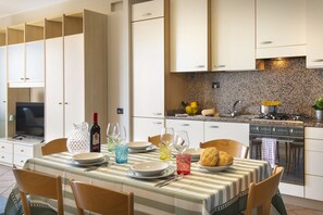 A modern kitchen with a dining area, equipped with a stove, sink, and various kitchen utensils.