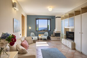A modern living room with a sofa, two chairs, a TV, and a fireplace. - Apartment Montegolo Four With Pool And Lake View (Costermano)
