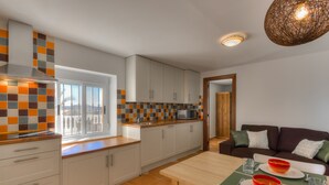 A modern kitchen with white cabinets, a tiled backsplash, and a dining area with a table set for two. - Villa Damara, luxury apartment Oliva, the place to relax! (Albox)
