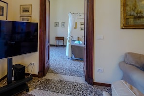 Una habitación con televisión, cama con dosel, una mesita y un sofá.