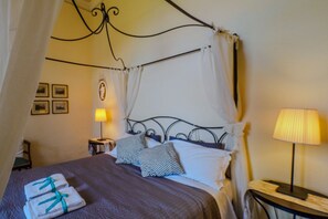 Una cama con dosel, una mesita de noche con lámpara y una pared con cuadros.