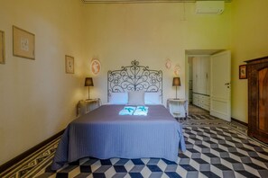 Un dormitorio con cama, dos mesitas de noche, un armario y suelo estampado.