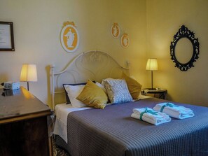 A hotel room with a bed, bedside tables, lamps, and decorative wall art.
