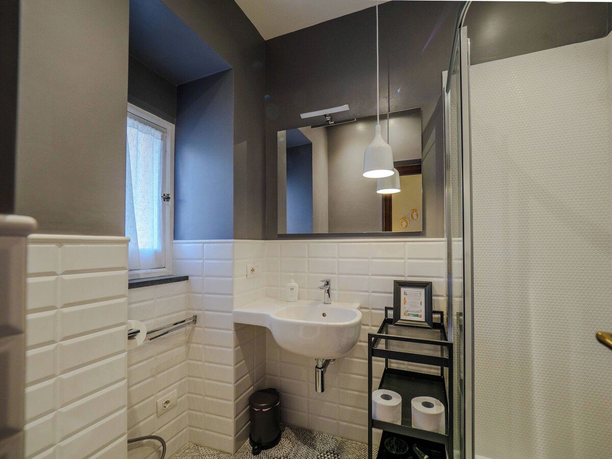 Une salle de bain avec un lavabo blanc, un miroir et un espace douche.