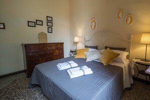 Una camera d'albergo con un letto, una cassettiera, un comodino e lampade a parete.