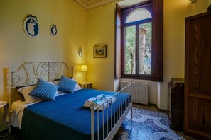 A bedroom with a bed, a window, a radiator, and a wooden door.