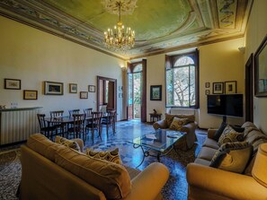 A spacious living room with a chandelier, sofas, a coffee table, and framed pictures on the walls.