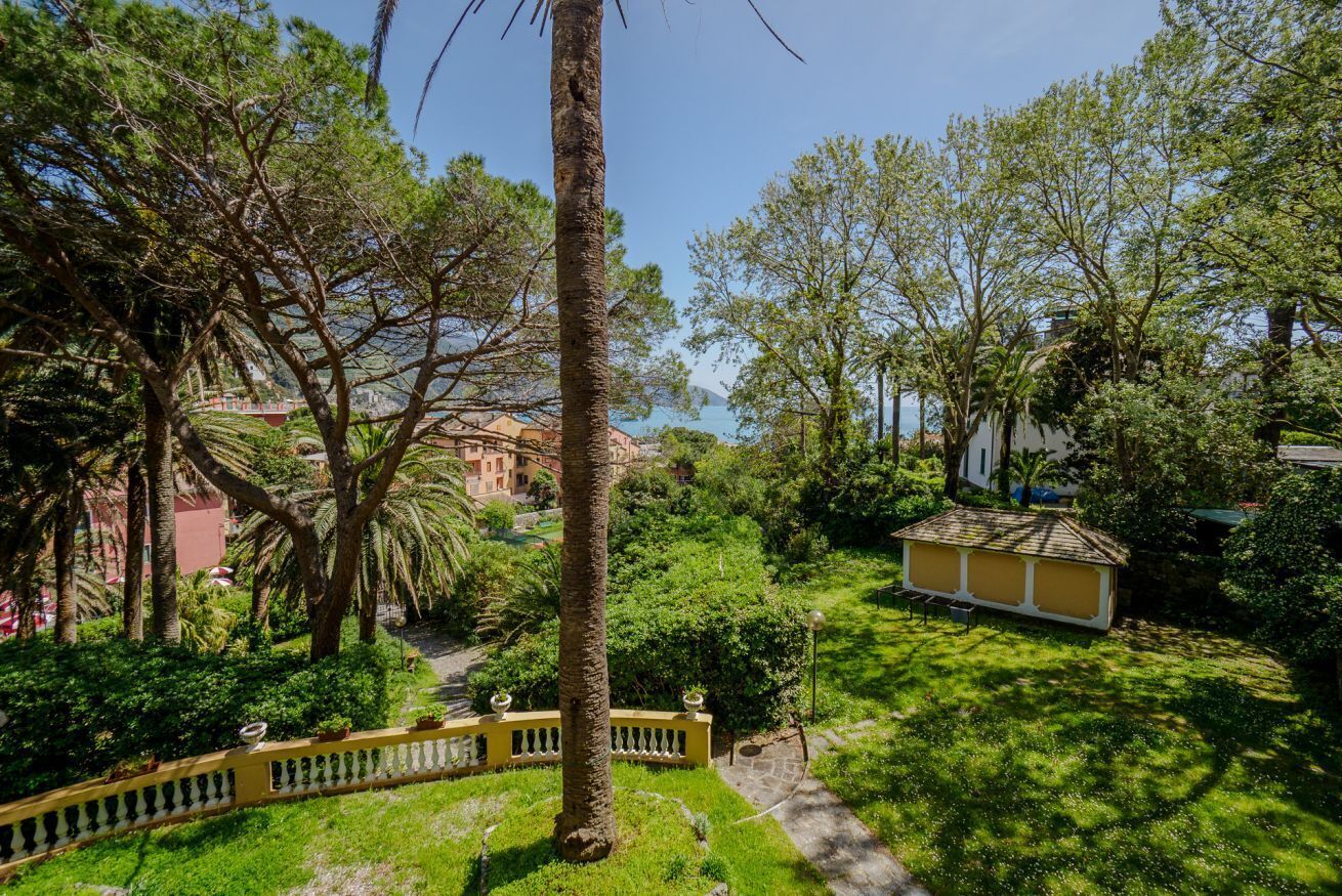 Un rigoglioso giardino con un vialetto, una recinzione gialla e un piccolo edificio.