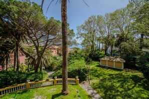 Un rigoglioso giardino con un vialetto, una recinzione gialla e un piccolo edificio.